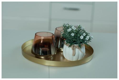 a gold tray with two glasses and a vase of flowers at Color 24 Apartament III in Stalowa Wola