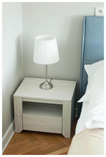 a white nightstand with a lamp on it next to a bed at Color 24 Apartament III in Stalowa Wola