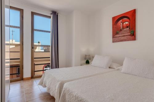 科拉雷侯的住宿－Apartamento Pizarro 2b，一间白色卧室,配有两张床和一个阳台