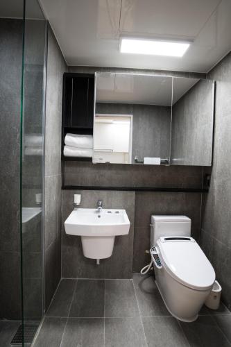 a bathroom with a toilet and a sink and a mirror at Sunrise Hotel Sokcho in Sokcho