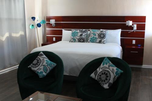 a bedroom with a bed with two green chairs at Hotel Cacaxtla in La Concordia