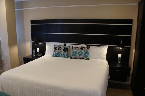 a bedroom with a large white bed with a black headboard at Hotel Cacaxtla in La Concordia