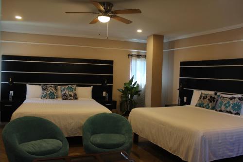 a bedroom with two beds and a fan and chairs at Hotel Cacaxtla in La Concordia