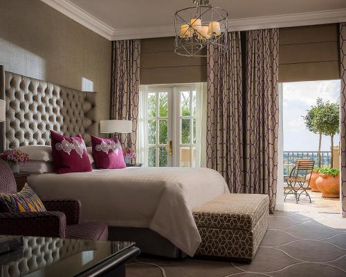 um quarto com uma cama grande e almofadas cor-de-rosa em Four Seasons Hotel The Westcliff em Joanesburgo