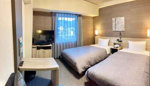 um quarto de hotel com duas camas e uma televisão de ecrã plano em Hotel Route-Inn Takefu Inter em Echizen