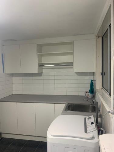 a kitchen with white cabinets and a sink at Shepp Central Apartment in Shepparton