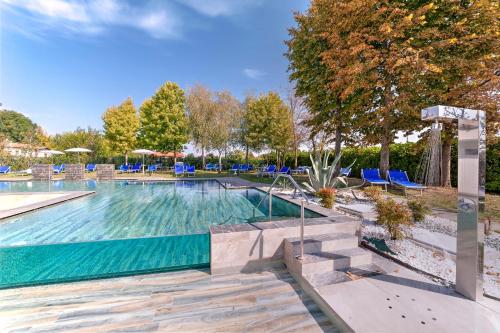 una gran piscina con sillas azules y árboles en Hotel Terme Belsoggiorno, en Abano Terme