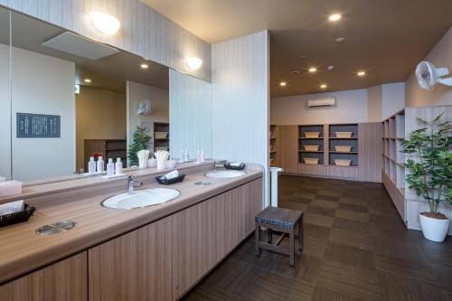 a bathroom with two sinks and a large mirror at HOTEL ROUTE-INN Chiba Hamano -Tokyowangan doro- in Chiba