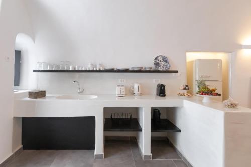 a white kitchen with a sink and a counter at Doukas Caldera Suites in Fira