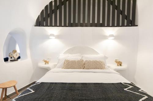 a bedroom with a bed with a black and white headboard at Doukas Caldera Suites in Fira