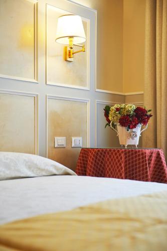 a bedroom with a bed and a vase of flowers on a table at Hotel Firenze Capitale in Florence