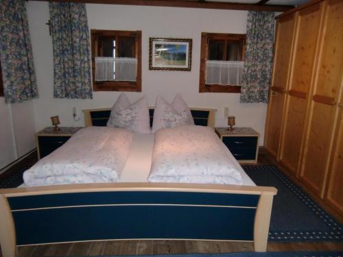 a bedroom with two beds and two windows at Ferienhäuschen Rahm in Hainzenberg