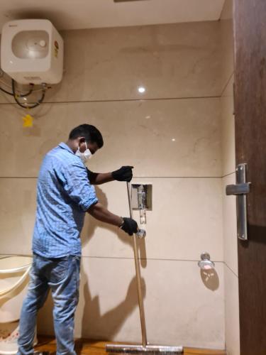 a man in a mask using a mop in a bathroom at Hotel Star Inn in Gangānagar