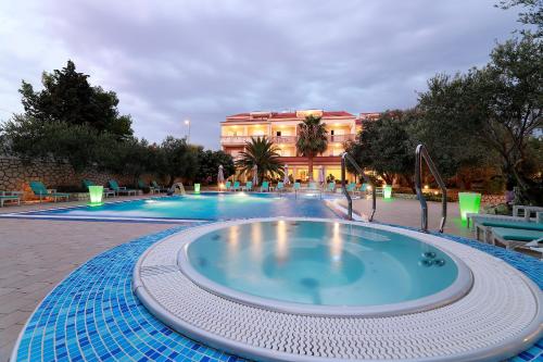 a large swimming pool with a large building in the background at Resort Trcol in Novalja