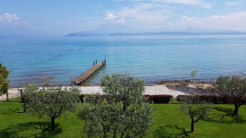 a dock in the middle of a body of water at Appartamento ORCHIDEA a Sirmione sul Lago di Garda con piscina, giardino e spiaggia con molo in Sirmione