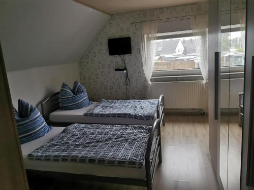zwei Betten in einem kleinen Zimmer mit Fenster in der Unterkunft Ferienhaus Thalia in Übach-Palenberg
