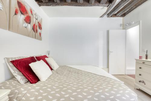 a white bedroom with a large bed with red pillows at Le petit Versailles T2 cosy proche Paris in Versailles