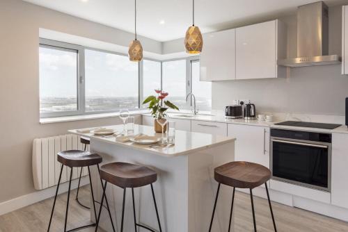 a kitchen with a white counter and stools in it at Metro Apartments Dublin Airport in Dublin
