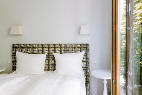 a bedroom with a bed with white pillows and a window at Jugend- und Familienhotel Augustin in Munich