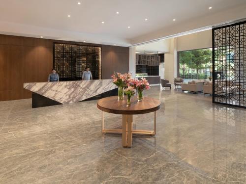 a lobby with a table with flowers on it at AIHO Hotel Medan in Medan
