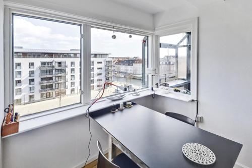 een kantoor met een bureau en 2 grote ramen bij Stille og hyggelig lejlighed in Kopenhagen