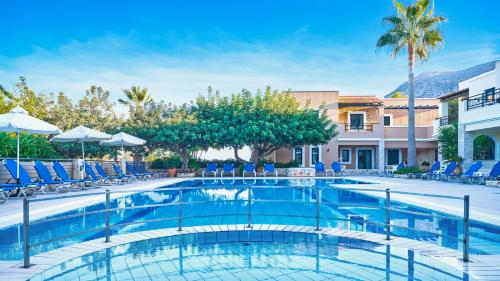 a swimming pool with chairs and umbrellas at Dionysos Apartments & Studios in Stalida