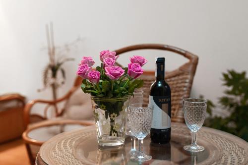 a table with a bottle of wine and a vase of pink flowers at Negroni Apartments Stare Miasto in Krakow