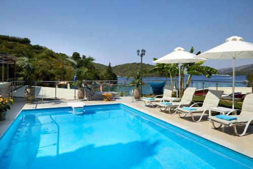 a swimming pool with chairs and umbrellas next to the water at Karvouno Villas in Sivota
