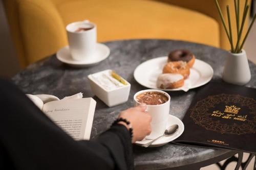 a person sitting at a table with coffee and donuts at Taj Al Worood in Jeddah