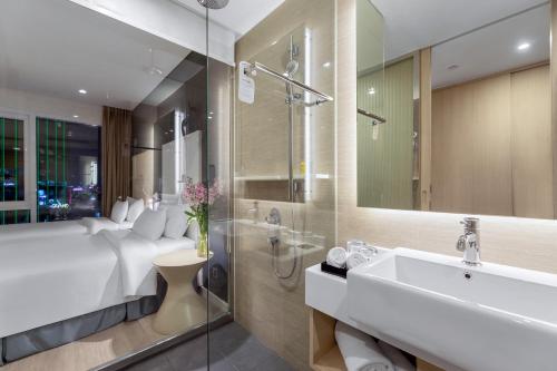 y baño con cama, lavabo y espejo. en Liberty Central Saigon Riverside Hotel en Ho Chi Minh