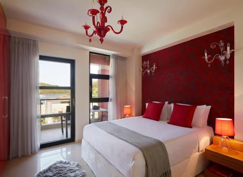 a bedroom with a large bed with red walls and a chandelier at Karvouno Villas in Sivota