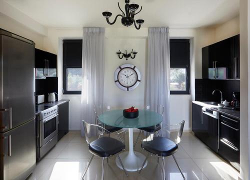 a kitchen with a table and chairs and a clock at Karvouno Villas in Sivota