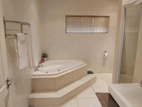 a white bathroom with a tub and a sink at Hush Guest House in Northam