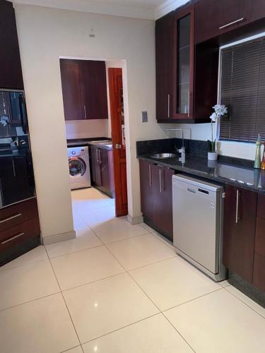 a large kitchen with brown cabinets and appliances at Hush Guest House in Northam
