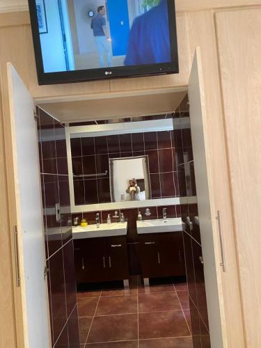 a bathroom with a tv on the wall and a mirror at Hush Guest House in Northam