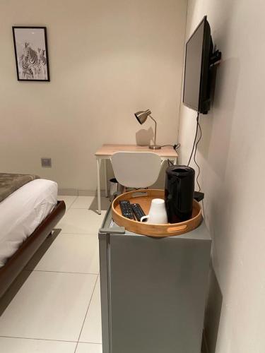 a room with a bed and a desk with a television at Hush Guest House in Northam