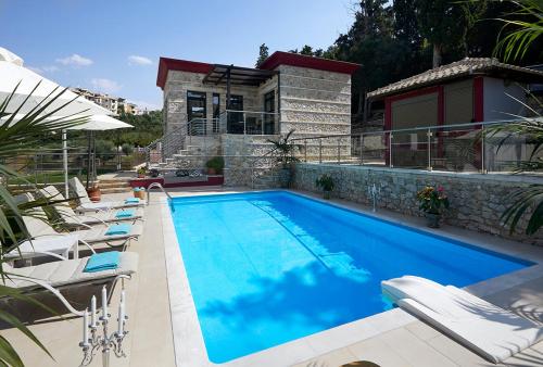a swimming pool with chairs and a house at Karvouno Villas in Sivota