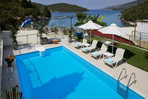 a large blue swimming pool with chairs and umbrellas at Karvouno Villas in Sivota