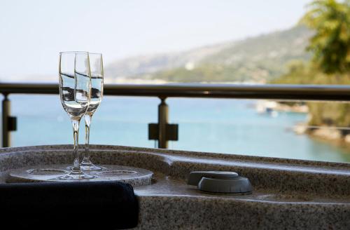 a wine glass on a table with a view of the water at Karvouno Villas in Sivota