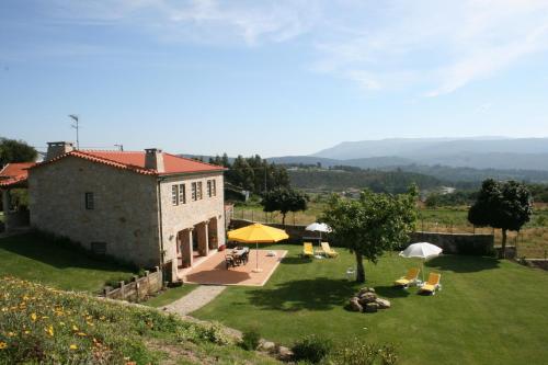 a building with a yard with chairs and umbrellas at Casa Da Oliveirinha in Casco