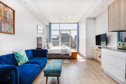 Una sala de estar con un sofá azul y una cama. en Backup-Power Eclectic Blue City View Apartment, en Ciudad del Cabo