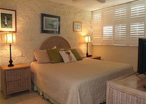 a bedroom with a bed with two lamps and a television at Kanai A Nalu Resort 205 in Wailuku