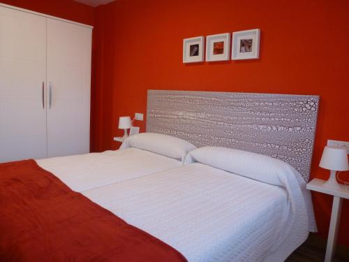 Eulz的住宿－Casa rural Navarra accesible para grupos grandes de 14-16 personas Belastegui II，一间卧室配有一张白色的床和橙色的墙壁
