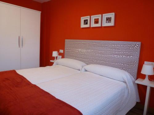 a bedroom with a white bed with an orange wall at Casa rural Navarra para niños, accesible para grupos grandes de 14-16 personas Belastegui II in Eulz