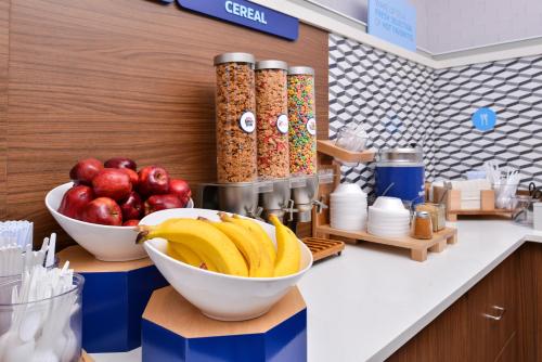 a counter with a bowl of bananas and apples at Holiday Inn Express Hotel & Suites Cincinnati - Mason by IHG in Mason