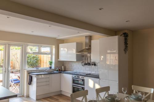 una cocina con armarios blancos y una mesa con sillas. en Merewood House, en Oxford