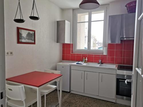 - une cuisine avec une table, un évier et du carrelage rouge dans l'établissement Chez Camille, à Reims