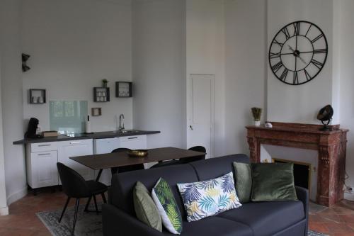 sala de estar con sofá y reloj en la pared en Paul Sabatier-T1-Vue sur Jardin-Luxe-wifi-fi-vélo, en Castelnaudary