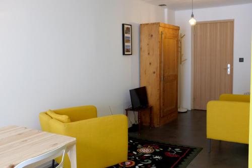 a living room with two yellow chairs and a television at Iglusaq Lodge in Veysonnaz