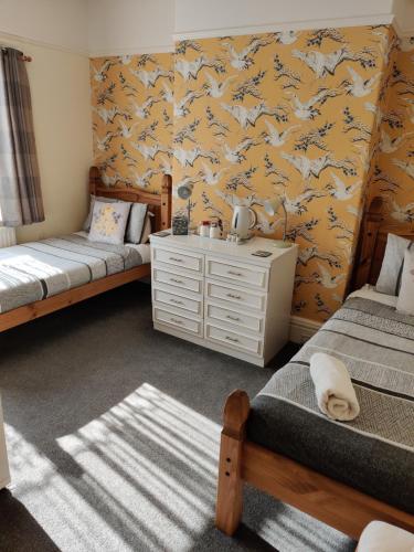 a bedroom with two beds and a yellow wall with wolves at Cameron court B&B in Flamborough